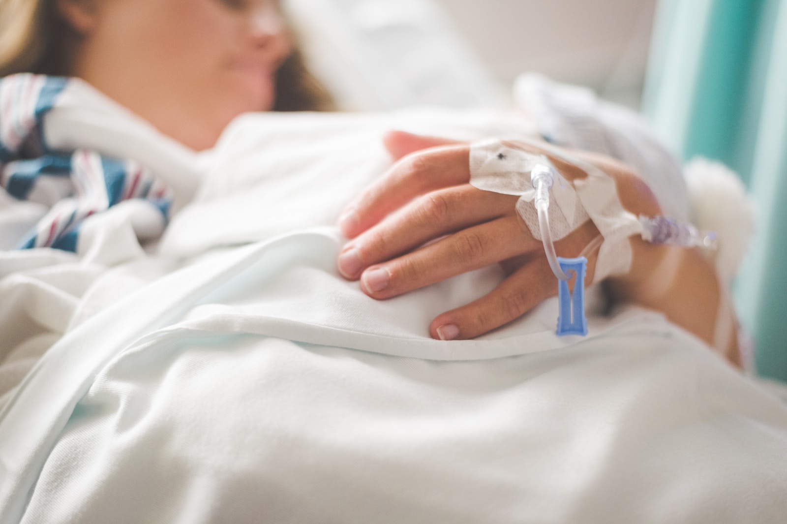 kvinne i sykehusseng med veneflon i armen